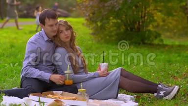 秋日公园的男女在草坪上，喝着咖啡喝着果汁